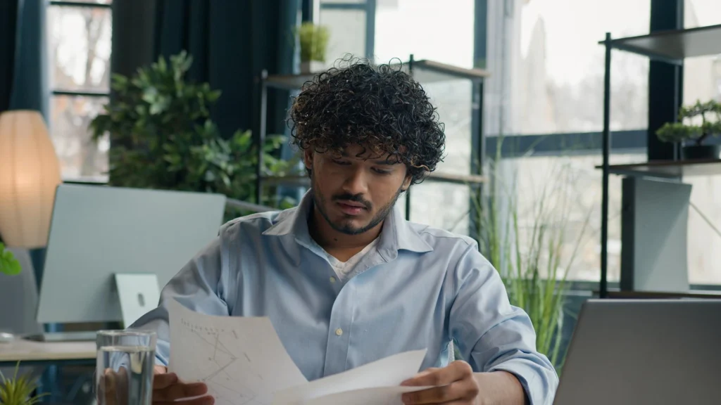 Focused businessman business person accountant office worker writing ideas in notebook paperwork Arabian Indian student write