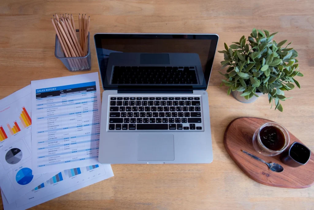 Office laptop business financial document chart and graph on wooden table with coffee cup Flat lay notebook computer laptop o